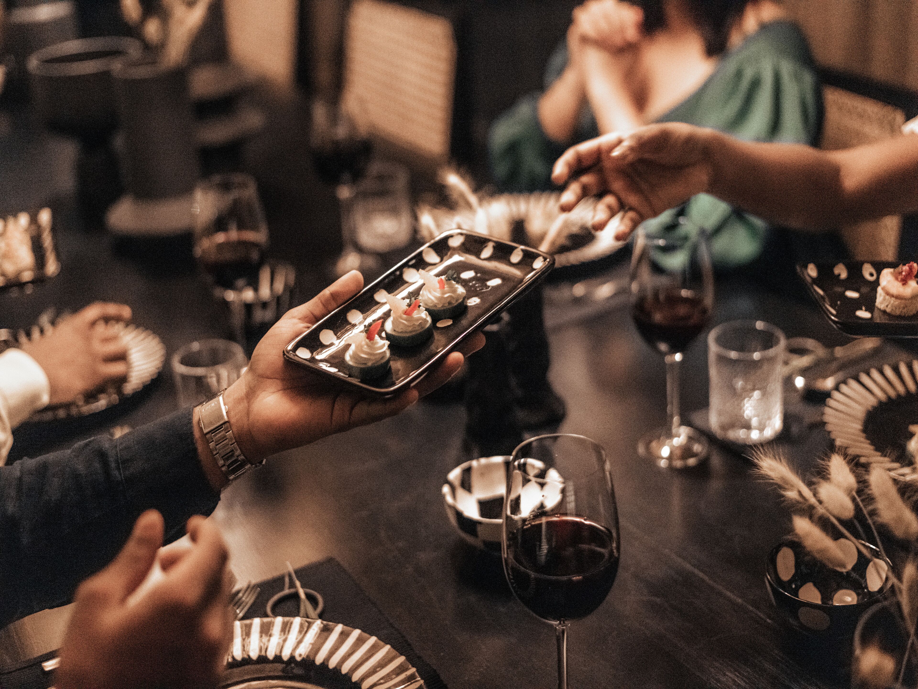 A group of people dining at a table with various dishes and glasses of wine.