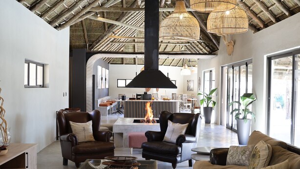 A spacious living area with leather sofas, a glass coffee table, and a fireplace.