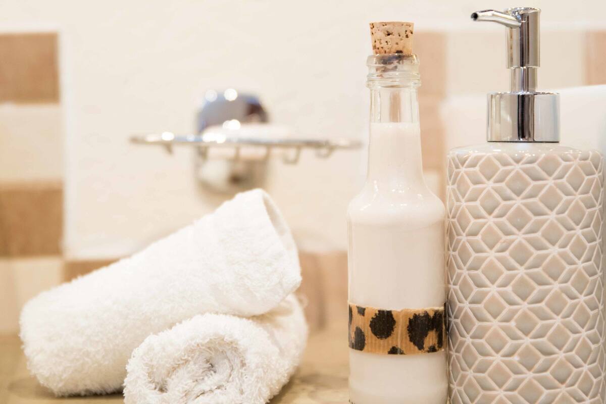 A bathroom with a towel, a bottle, and a soap dispenser on a countertop.