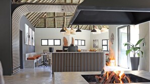 A modern kitchen with a central island, a fire feature, and a seating area with a bench and ottoman.