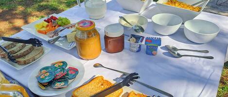A picnic setup with food items, a pitcher, and utensils on a table.