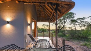 An outdoor seating area with a thatched roof, a table, and chairs.