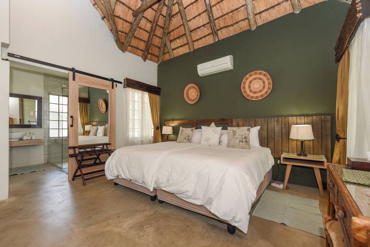 A bedroom with a bed, bedside tables, a mirror, and a ceiling fan.