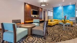 A hotel lobby with a seating area, a television, and a decorative wall.