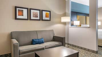 A hotel room with a sofa, a coffee table, and three framed pictures on the wall.