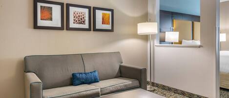 A hotel room with a sofa, a coffee table, and three framed pictures on the wall.