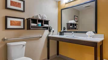 Un bagno d'albergo con un WC, un lavandino, uno specchio e spazio per asciugamani.