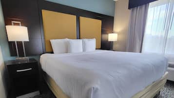 A hotel room with a large bed, two bedside tables, and a window with curtains.