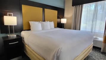 Habitación de hotel con una cama grande, dos lámparas de noche, una mesita de noche y una ventana con cortinas.