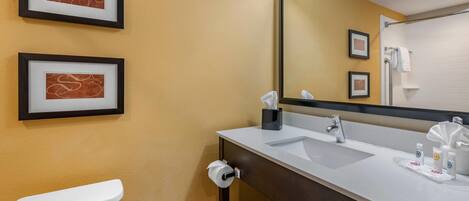 A bathroom with a toilet, a sink, a mirror, and two framed pictures on the wall.