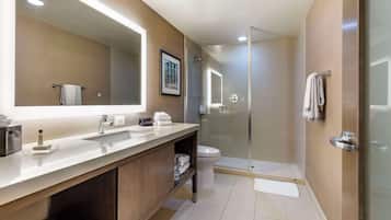 A modern bathroom with a large mirror, a sink, a toilet, and a glass-enclosed shower.