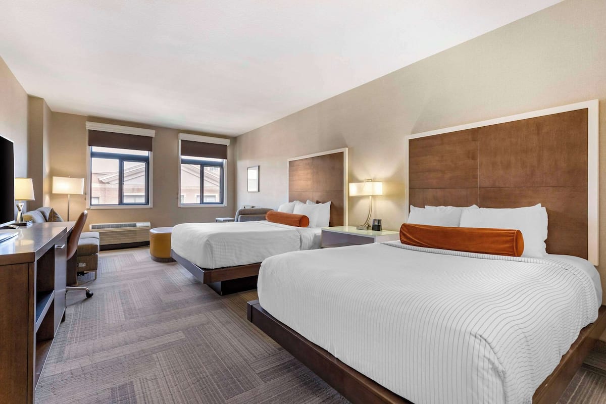 Een hotelkamer met twee bedden, een bureau, een stoel en een televisie.