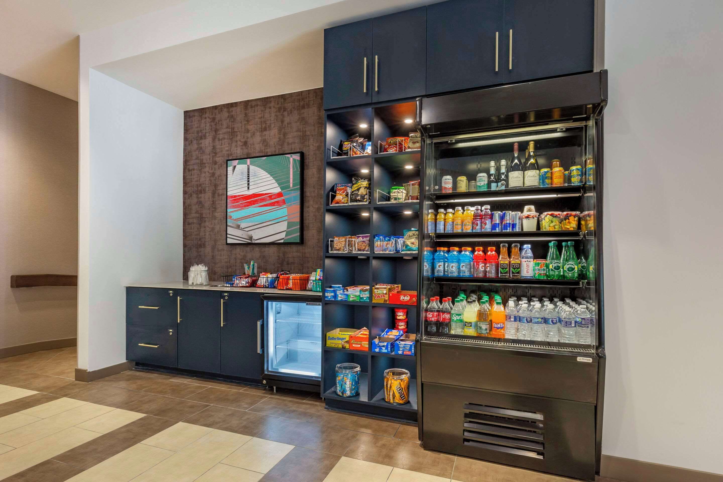 Een kitchenette met een koelkast vol drankjes, een magnetron en een kleine koelkast.
