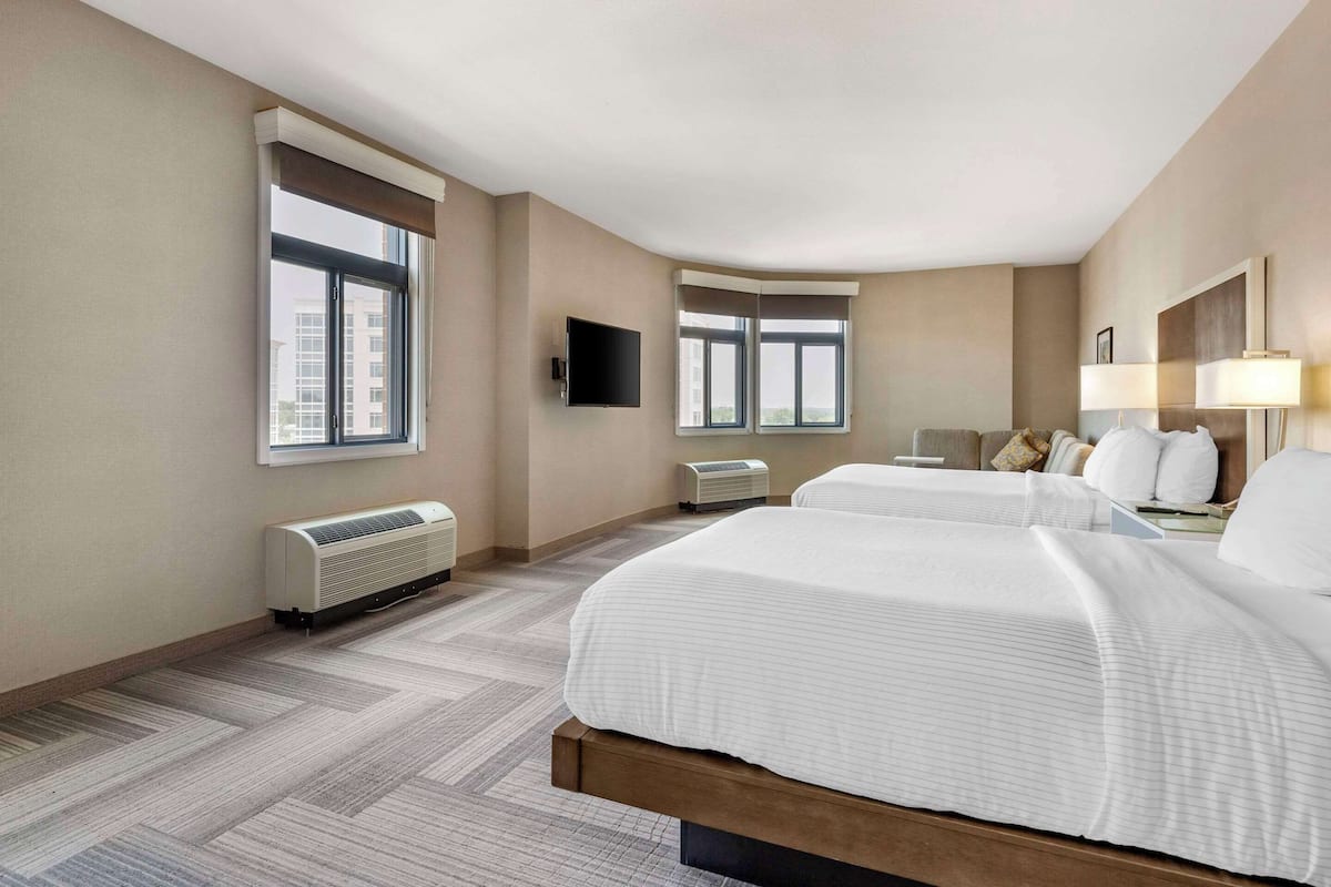 Een hotelkamer met twee bedden, een flatscreen televisie, een raam, een verwarming en een lamp.