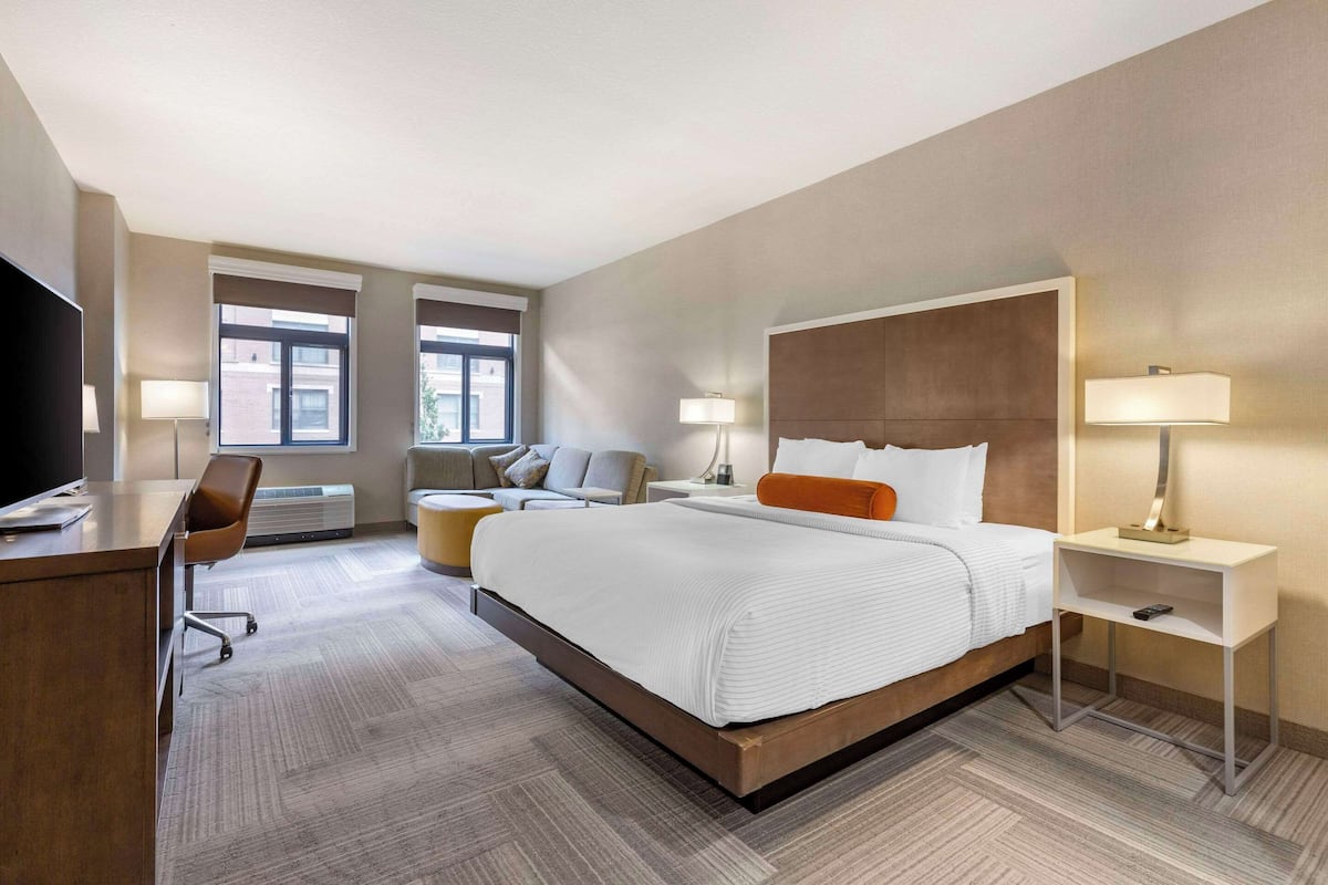 Een moderne hotelkamer met een groot bed, een bureau, een stoel en twee nachtkastjes met lampen.