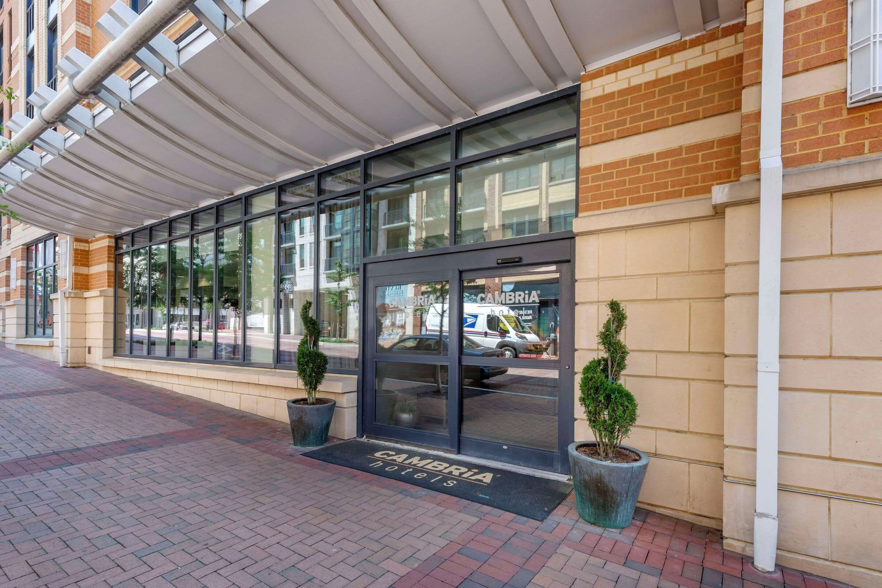 A hotel entrance with a modern design, featuring large glass windows and a covered walkway.