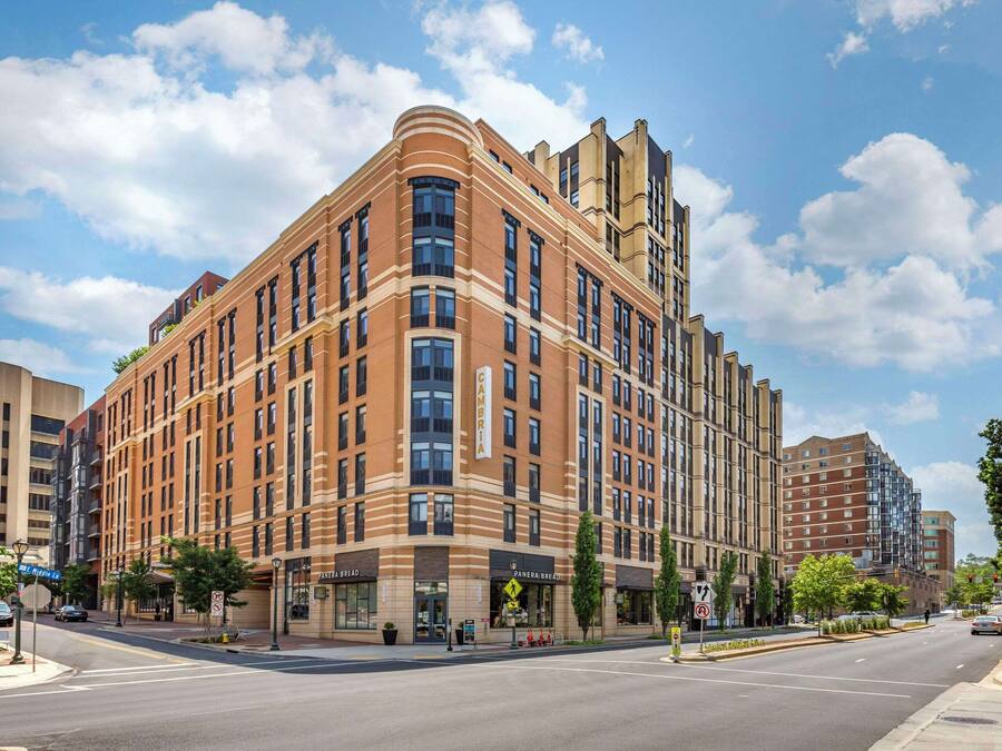 A multi-story hotel with a prominent corner entrance, large windows, and a visible sign for Panera Bread.