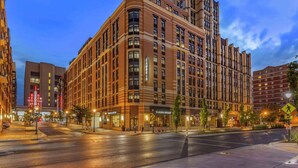 A multi-story hotel with a corner entrance, large windows, and a prominent 'Panera Bread' sign.