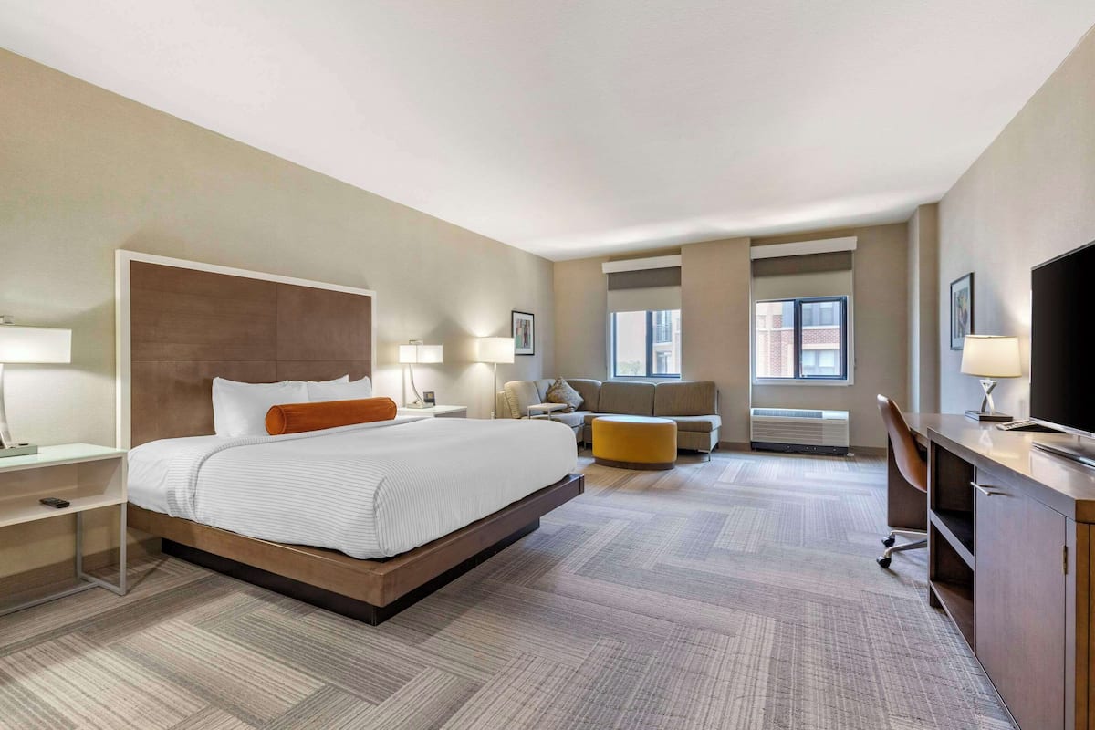 Een hotelkamer met een groot bed, een bureau, een stoel, een bank en een televisie.