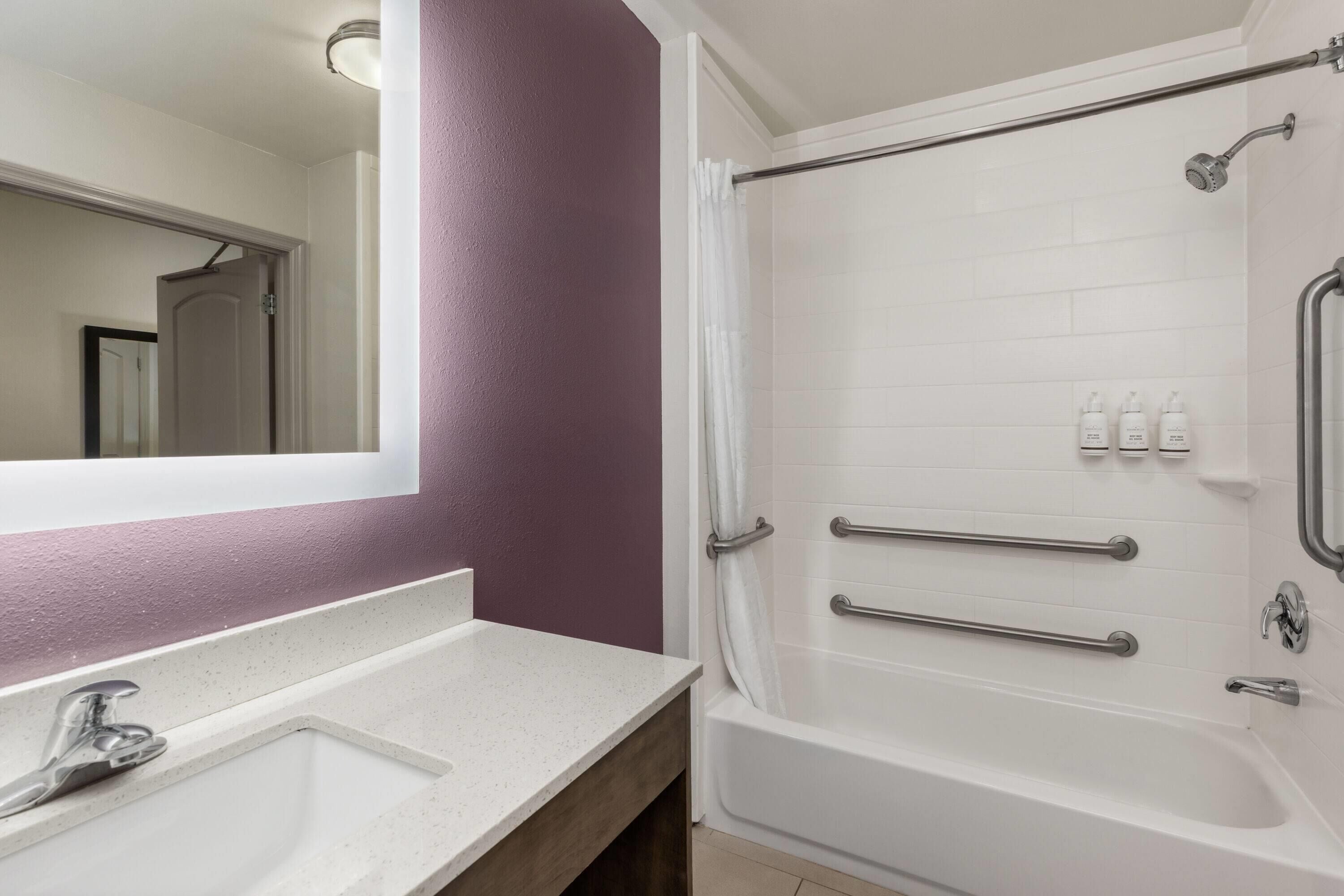 A bathroom with a white sink, mirror, and shower area.