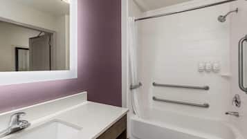 A bathroom with a white sink, mirror, and shower area.