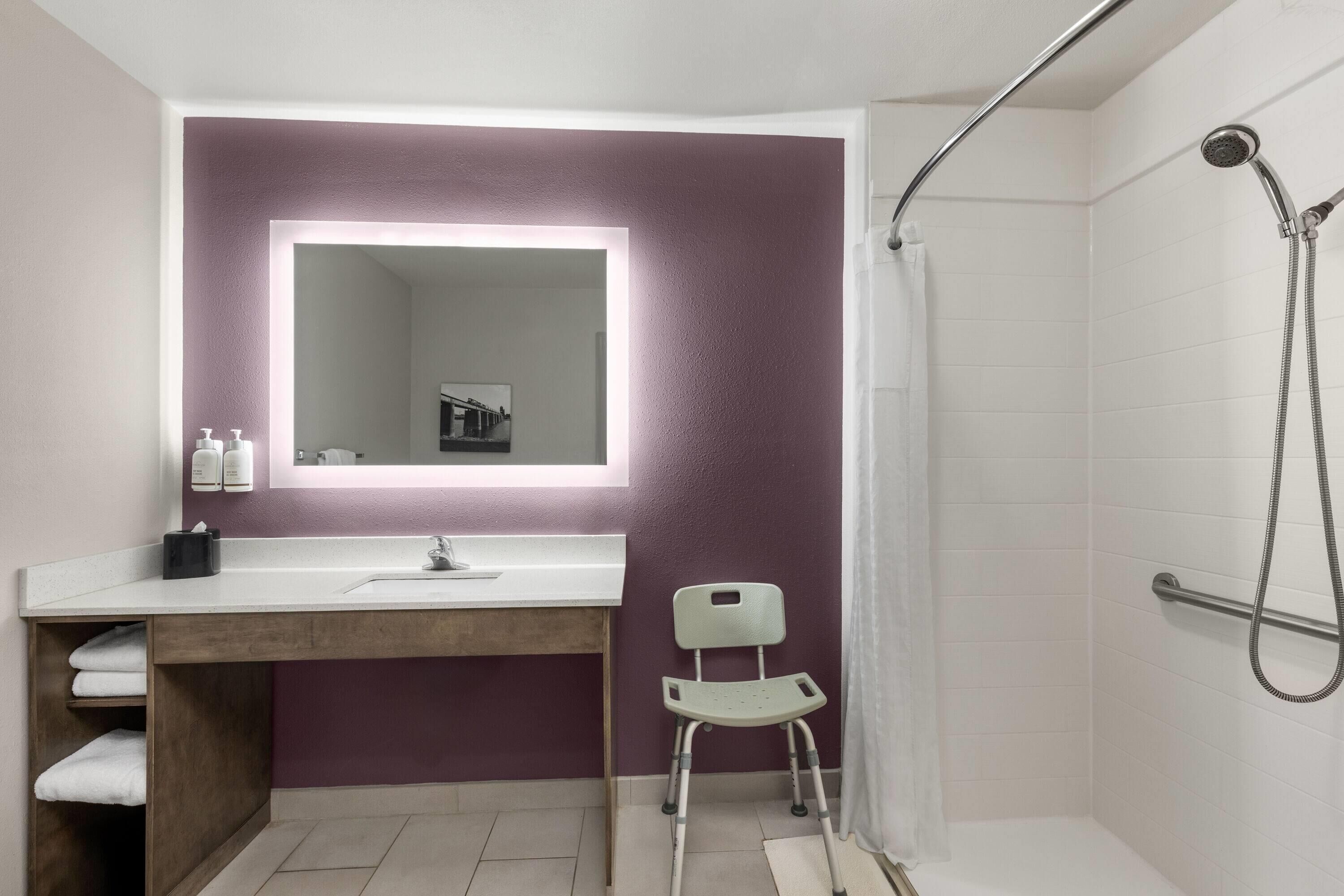 Une salle de bain équipée d’un meuble-lavabo, d’une douche et d’un siège accessible aux personnes en fauteuil roulant.