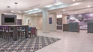 Un hall d’hôtel moderne, doté d’un grand téléviseur, d’un tapis à motifs et d’une fresque murale.