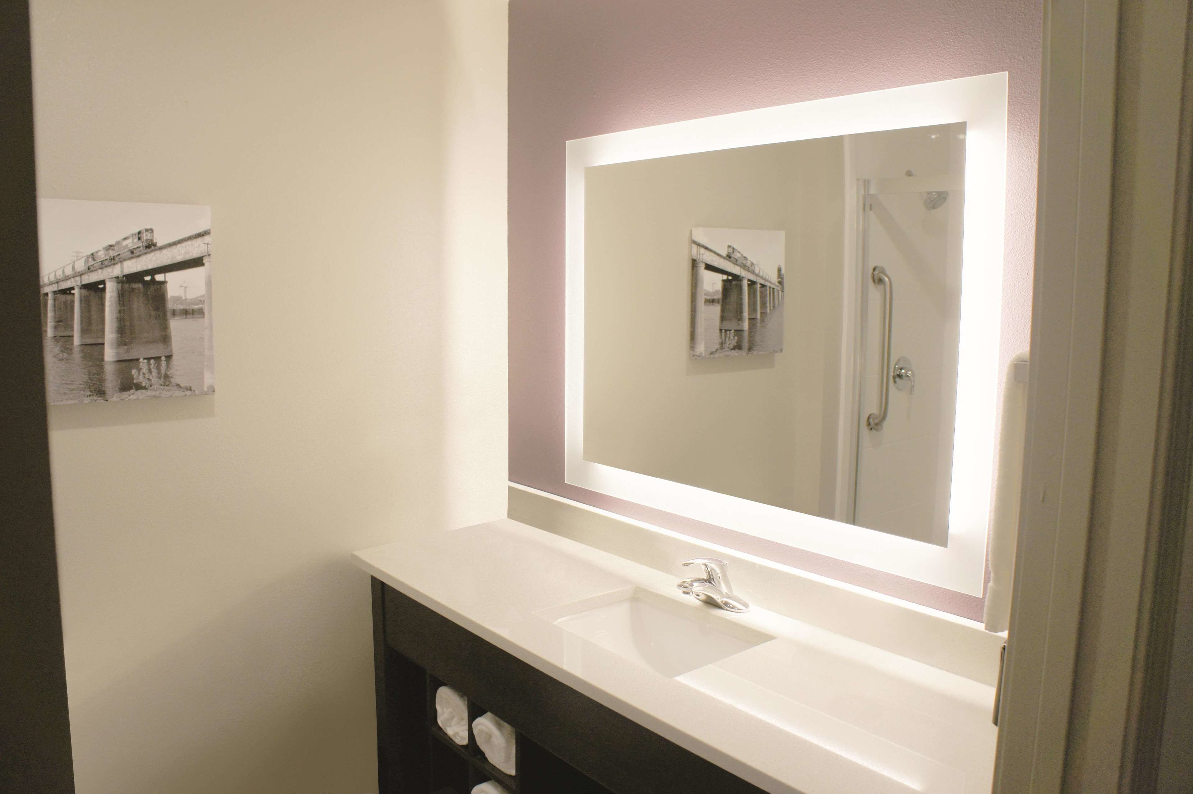 A bathroom with a large mirror, a sink, and a shower.