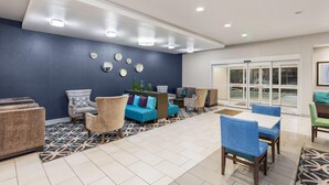 Un espace de détente moderne avec un mur bleu, une moquette à motifs et divers types de sièges, notamment des canapés et des fauteuils.