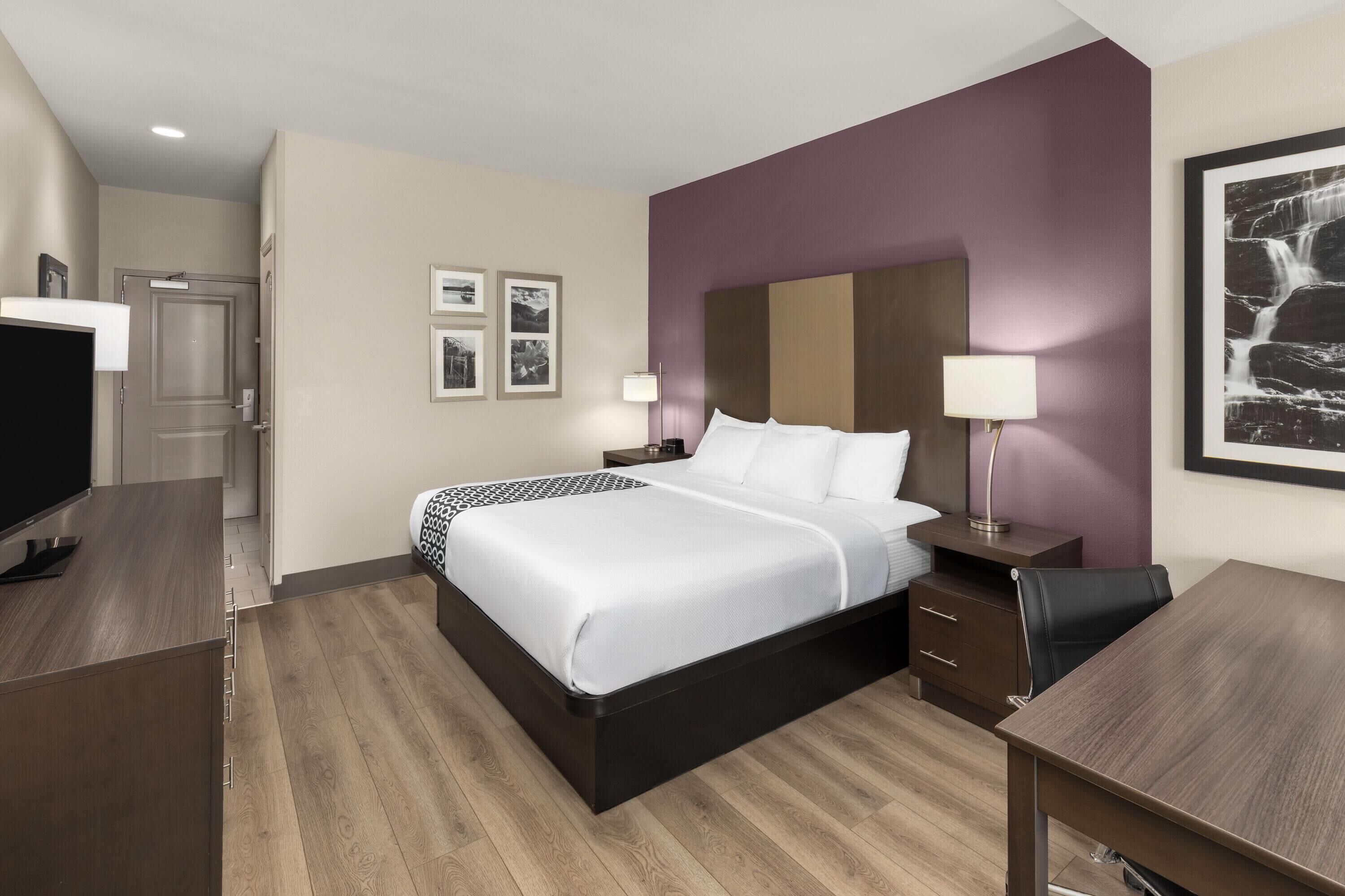 Une chambre d’hôtel moderne, dotée d’un grand lit, de tables de chevet, d’un bureau et d’une télévision.