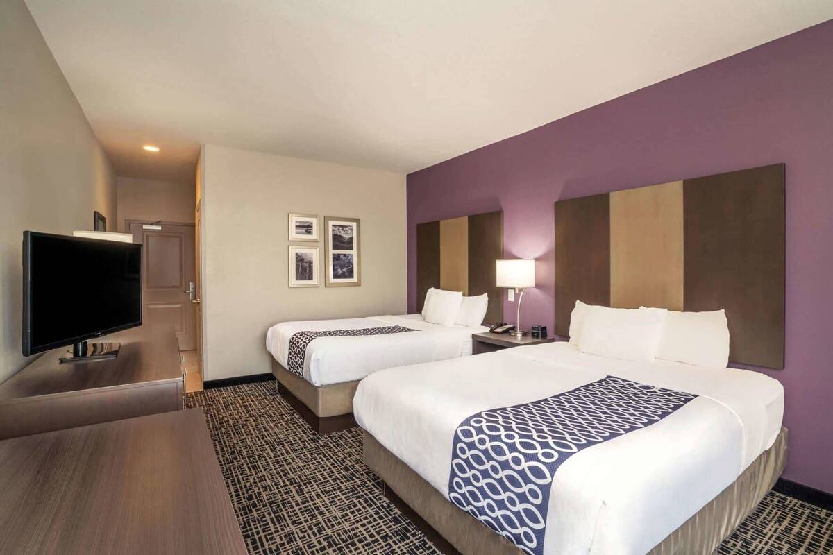 Une chambre d’hôtel avec deux lits, une télévision, un bureau et un tapis à motifs.