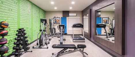 Un gimnasio con diversos equipos de ejercicio, incluyendo una cinta de correr, bicicleta estática y máquinas de pesas.