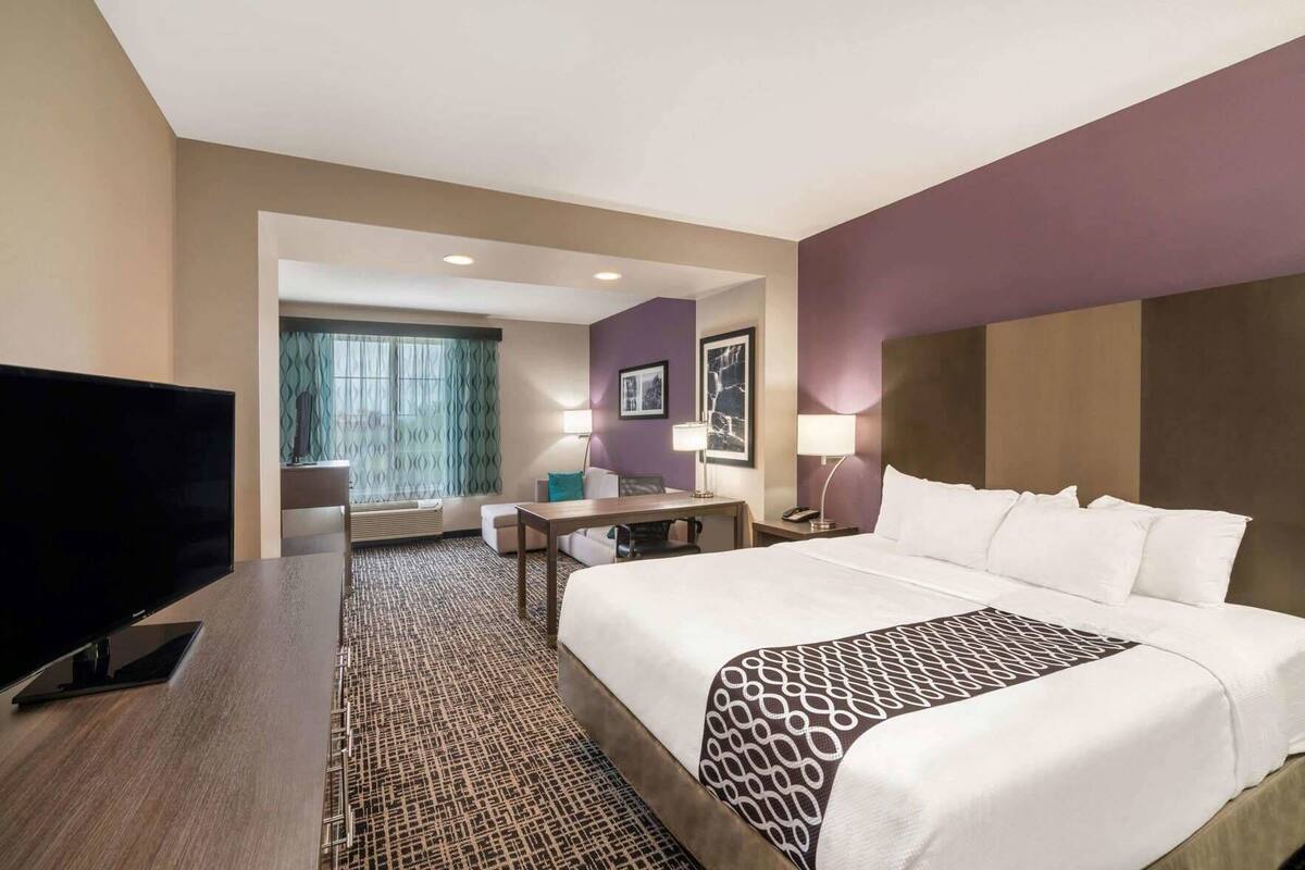 Une chambre d’hôtel avec un grand lit, un bureau, une télévision et une vue sur l’extérieur.