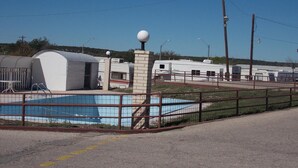 A recreational area with a swimming pool, RVs, and a fenced enclosure. - Holiday Host Motel (Sonora)