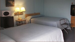 A hotel room with two beds, a desk with a lamp, a telephone, a TV, and a drying rack. - Holiday Host Motel (Sonora)