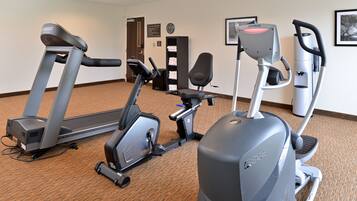 Un gimnasio con cintas de correr, elípticas y una bicicleta estática.