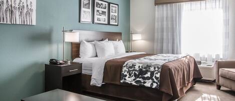 A hotel room with a bed, bedside table, lamp, and a view of the city skyline through the window.