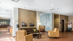 A spacious lobby with a brown sofa, two armchairs, a coffee table, and a decorative wall with white floral patterns. - Sleep Inn & Suites Meridian - Bonita Lakes (Meridian)