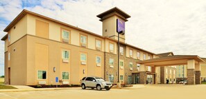 A modern hotel with a beige facade, multiple windows, and a covered entrance.