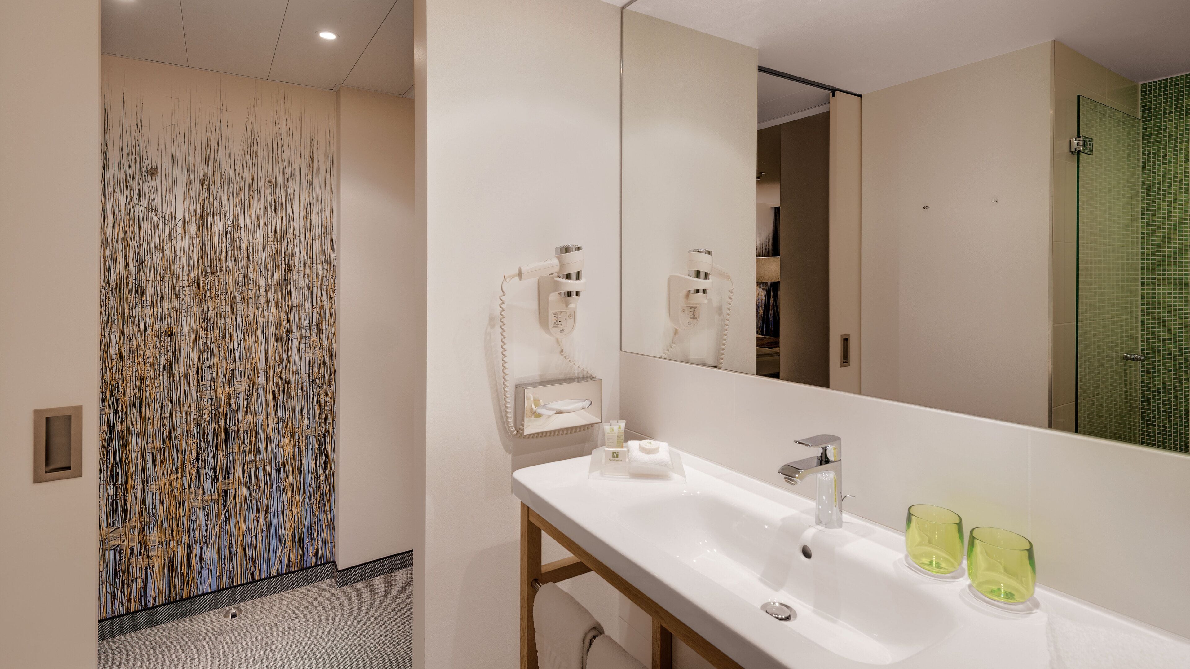 A modern bathroom with a large mirror, a white sink, and a glass shower enclosure.