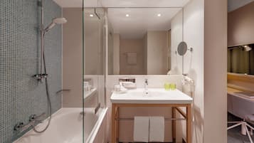 Ein modernes Badezimmer mit einer Duschkabine aus Glas, einem weißen Waschbecken mit Holzschrank und einem Spiegel mit Handtuchhalter.