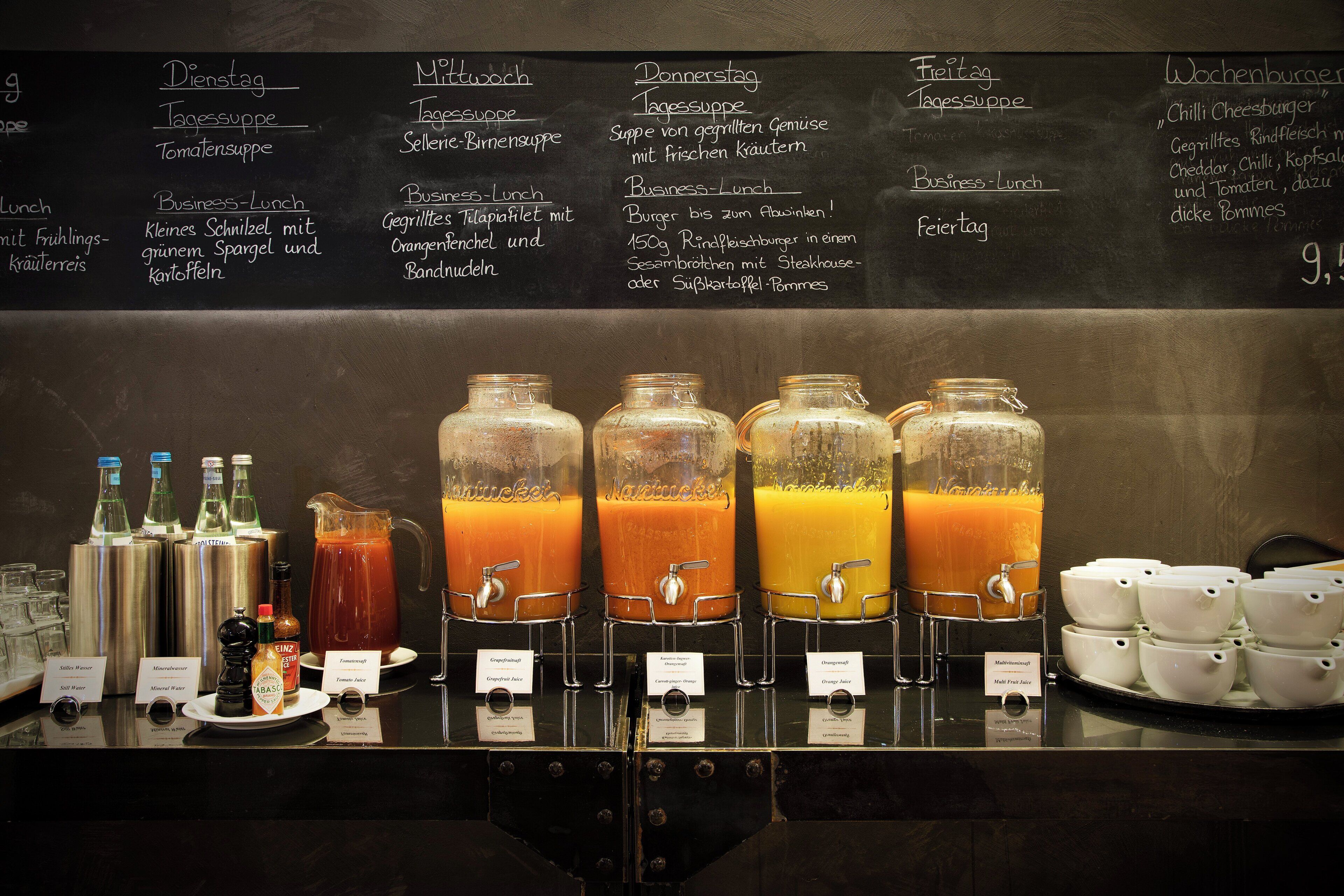 A beverage station with various drink dispensers and a menu board above listing food options.