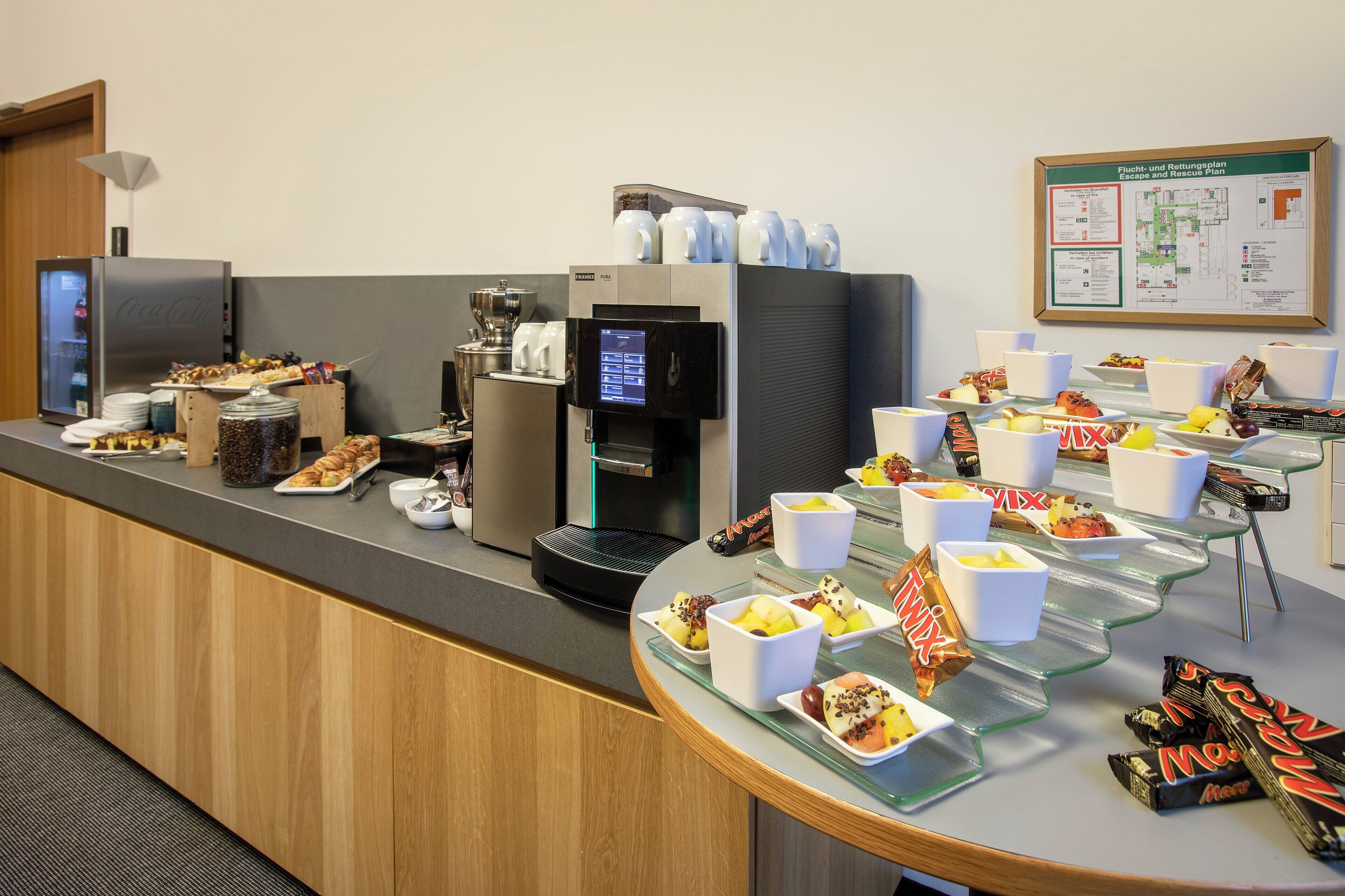 En morgenmadsbuffet med forskellige retter, en kaffemaskine og en vanddispenser.