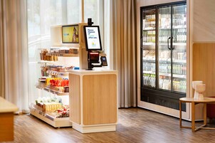 Un angolo bevande self-service con un banco frigo e uno schermo digitale.