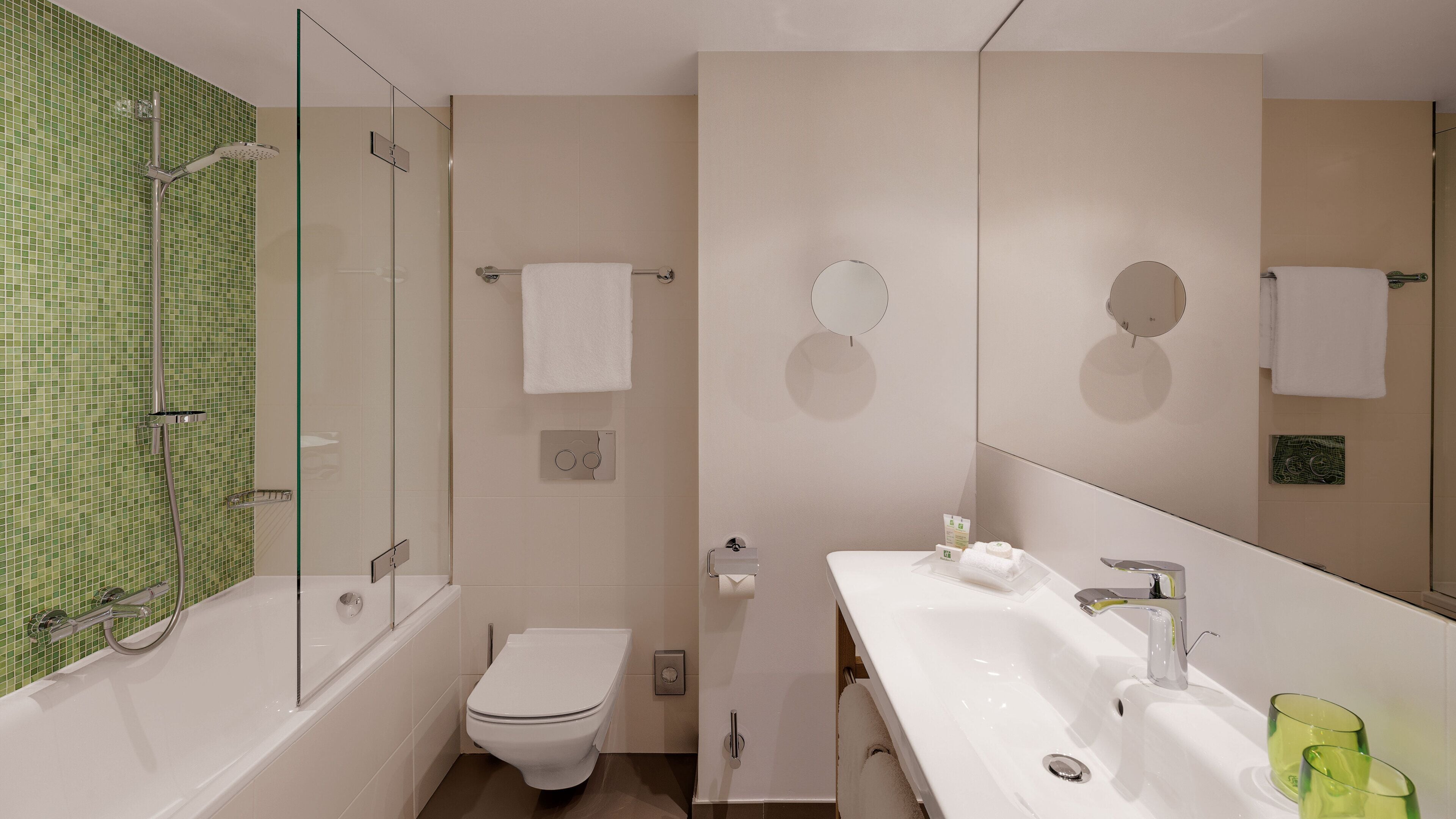 A modern bathroom with a glass-enclosed shower, a toilet, a sink with a mirror, and a towel rack.