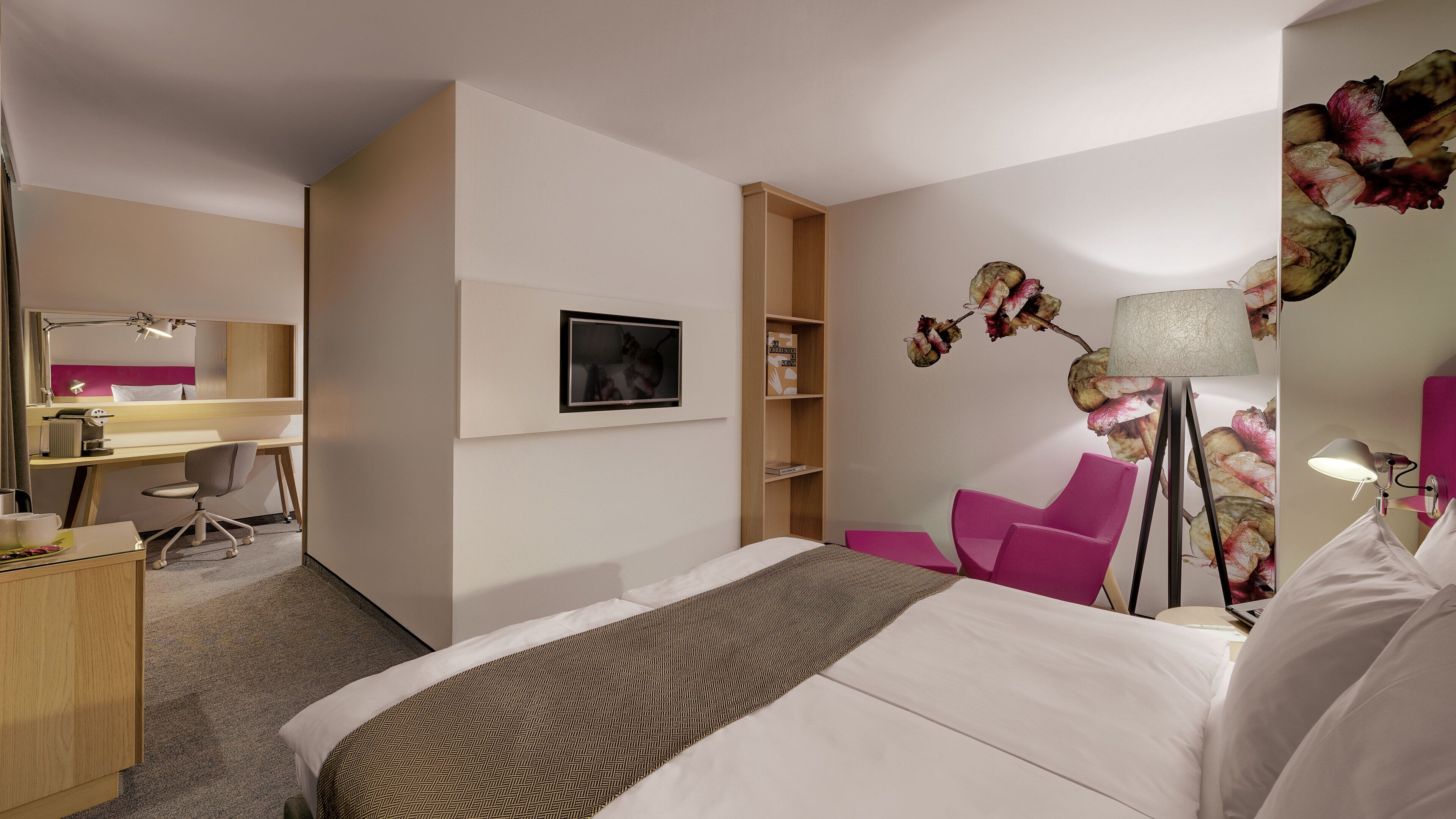 A hotel room with a bed, desk, chair, and a mirror.