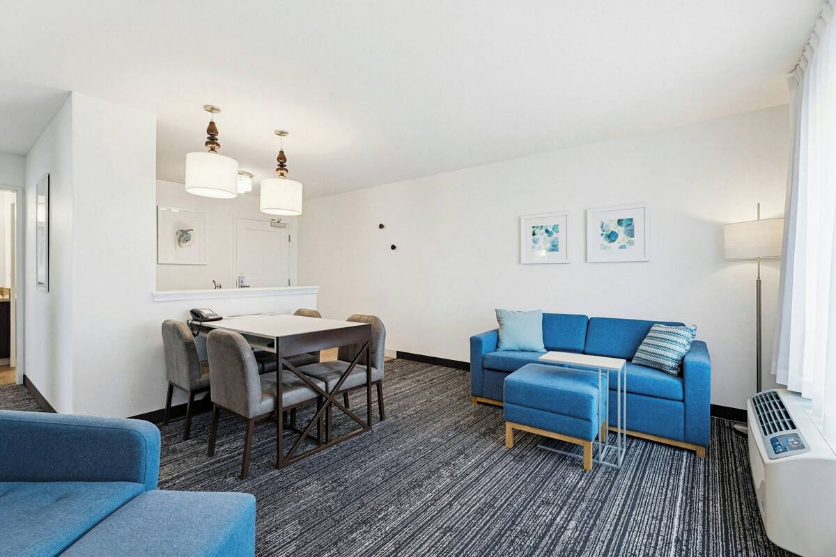 A modern hotel room with a dining area, a sofa, and a small table.
