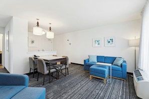 A modern hotel room with a dining area, a sofa, and a small table.
