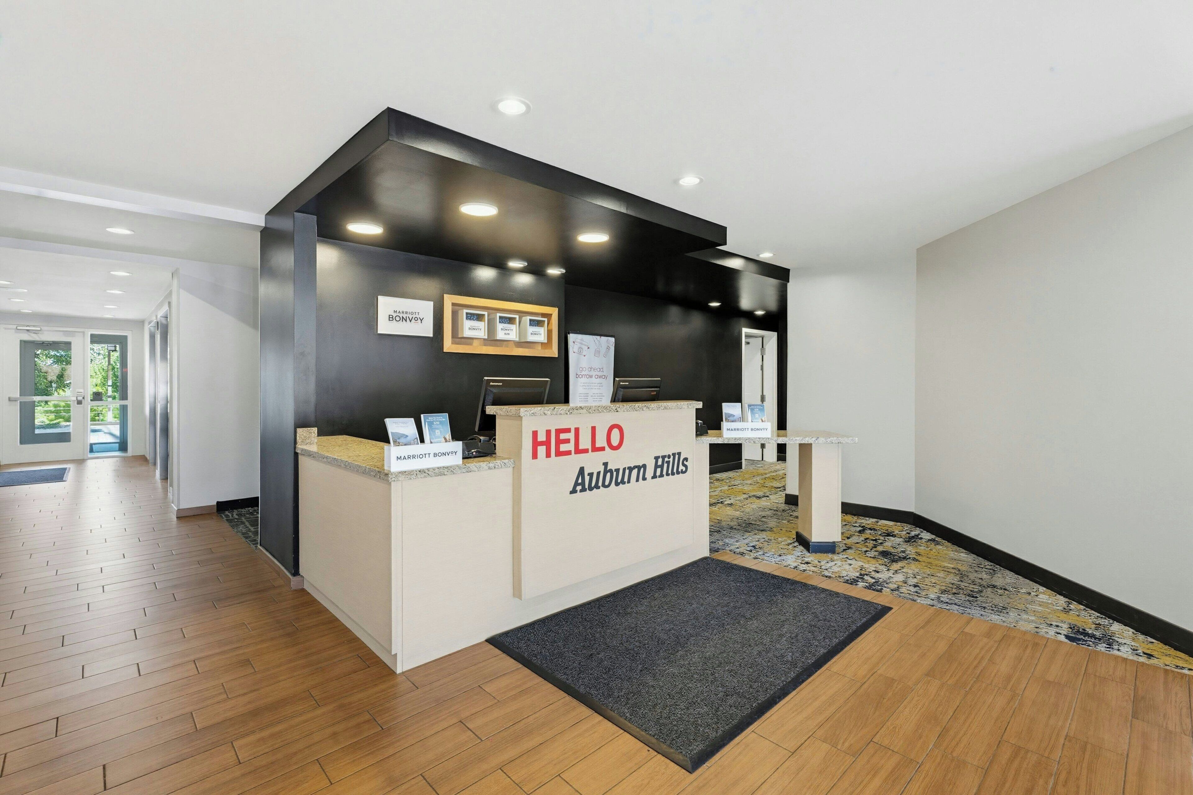 A reception desk with a sign reading 'HELLO Auburn Hills' and a framed picture above it.