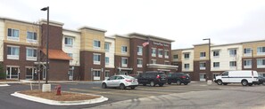 A TownePlace Suites Marriott hotel with a parking lot, multiple vehicles, and a fire hydrant.